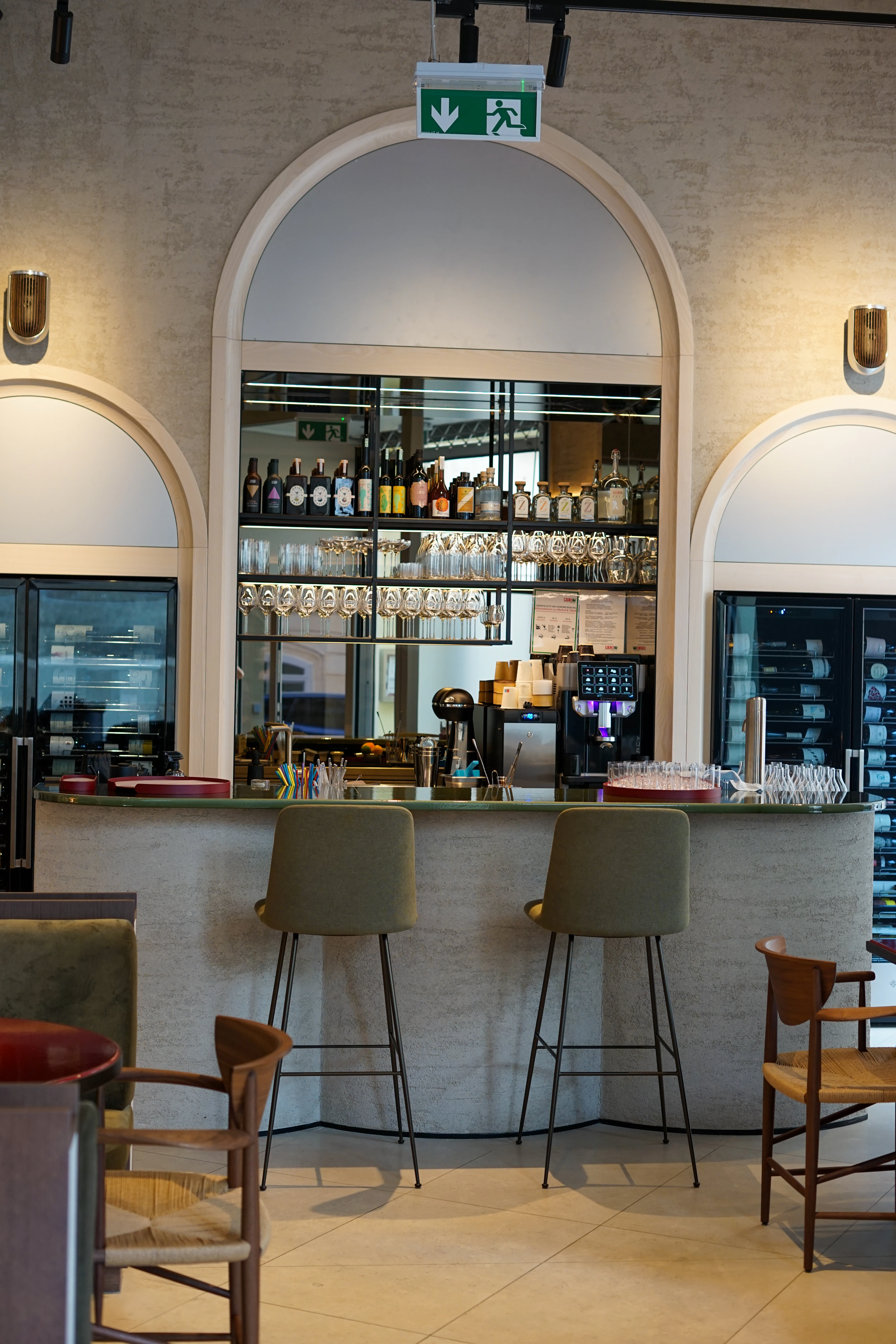 Innenaufnahme einer Bar oder eines Restaurants mit Hockern, Tischen und einer gut sortierten Bar.